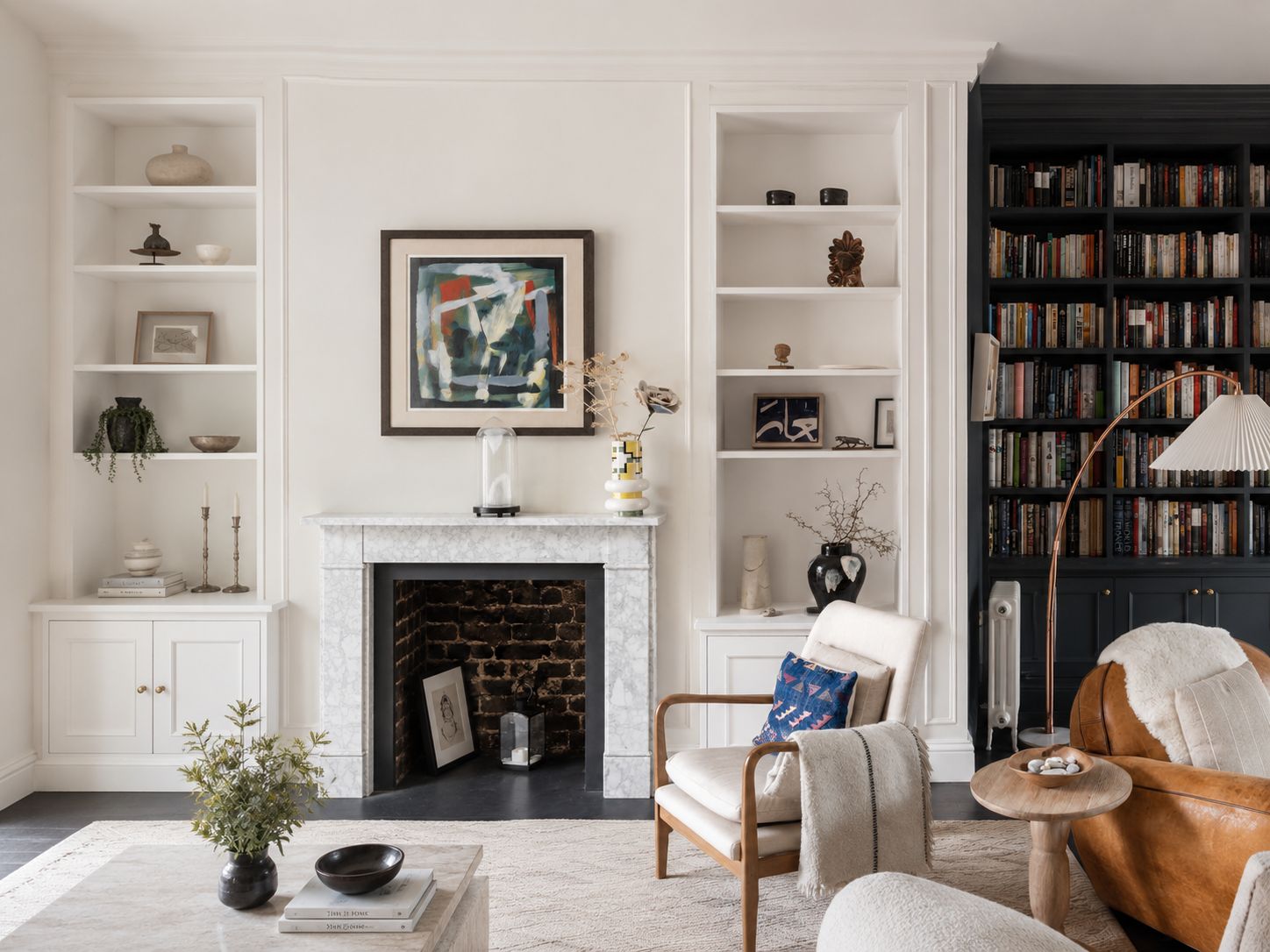 Bespoke alcove shelves with lower cabinets around a marble fireplace, with a contrasting dark fitted bookcase in the living room.