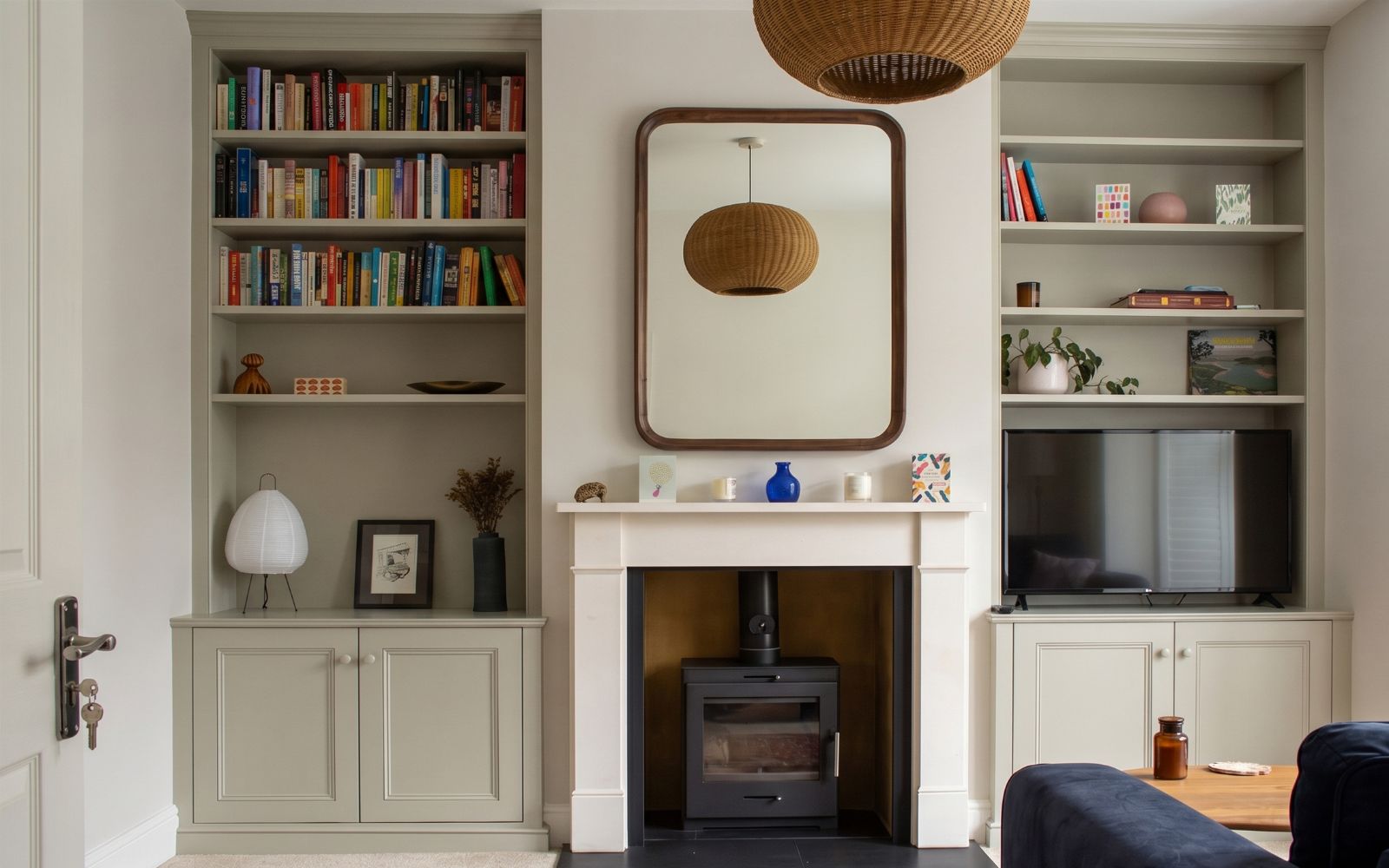 Bespoke fitted alcove shelving with lower cabinets, TV space and a wood-burning stove in a traditional living room.