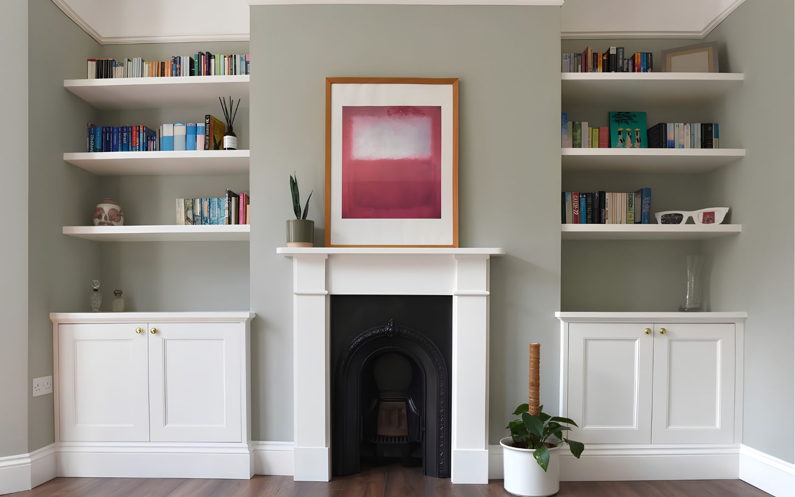Bespoke white alcove shelving with lower cabinets on either side of a traditional fireplace.