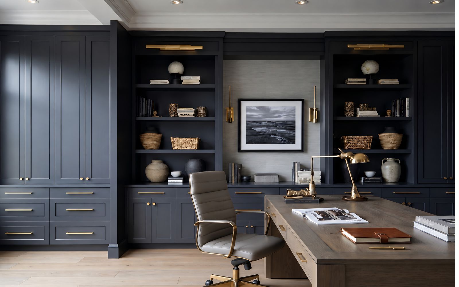 Dark bespoke fitted study with bookshelves, tall cupboards, desk and brass handles.
