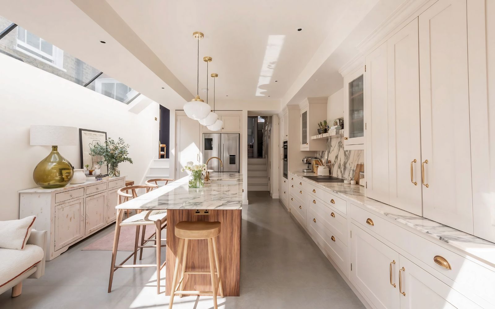 Bespoke in-frame shaker kitchen with hand-painted cabinetry, brass hardware, Calacatta marble worktops, and a walnut island, photographed in a light-filled London townhouse extension.